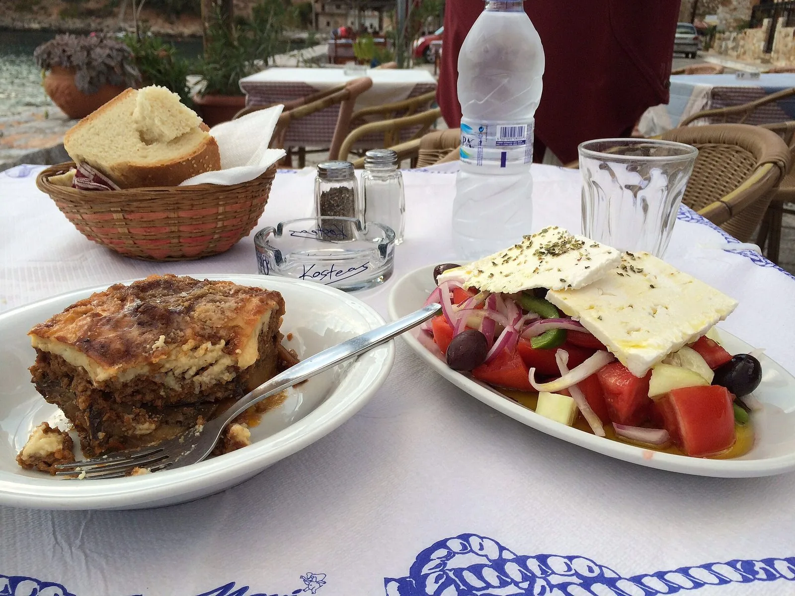 Un piatto di moussaka e un'insalata greca su un tavolo apparecchiato in taverna